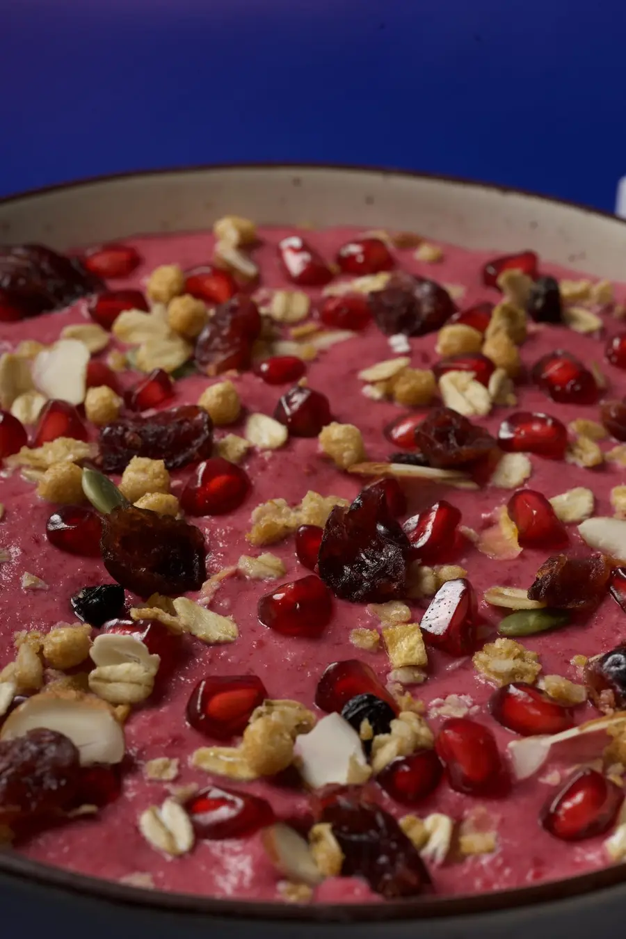 A pink berry smoothie bowl with pomegranate, cranberries and granola.